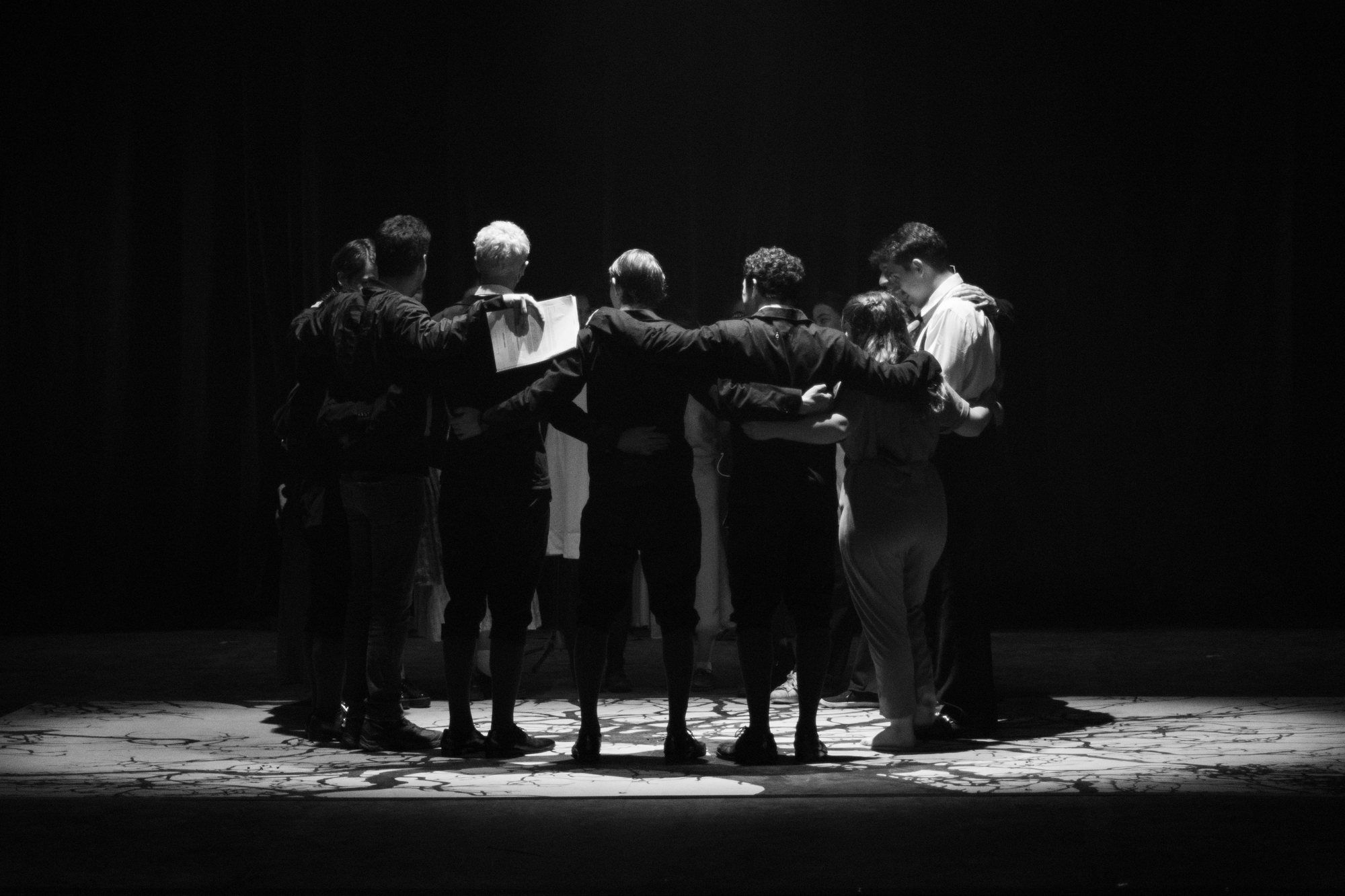 El elenco de Sueños del Despertar en ronda bajo una luz cenital.