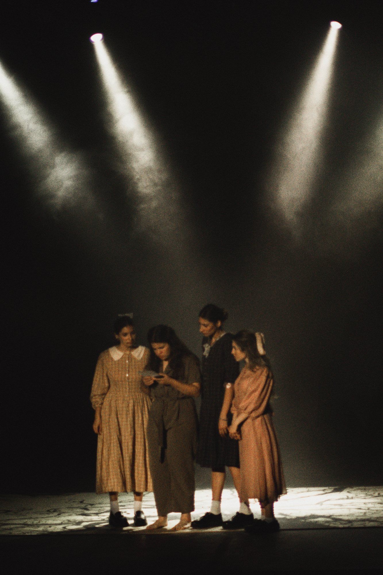 Cuatro actrices bajo dos haces de luz.