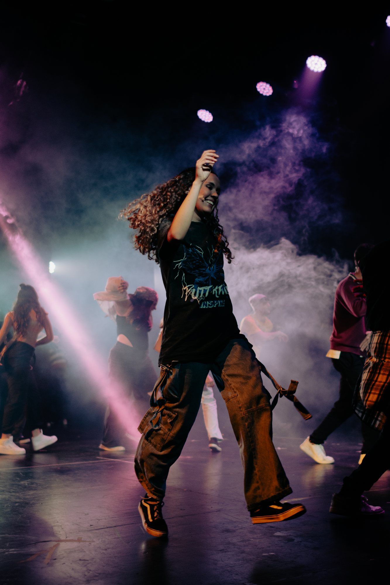 Una intérprete baila con luces rosas y humo.