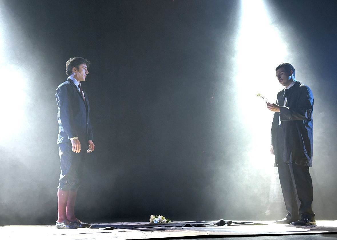 Dos actores enfrentados bajo dos haces de luz cenital con humo.